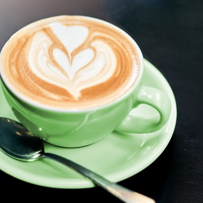 A drink with beautiful latte art in a green cup and saucer