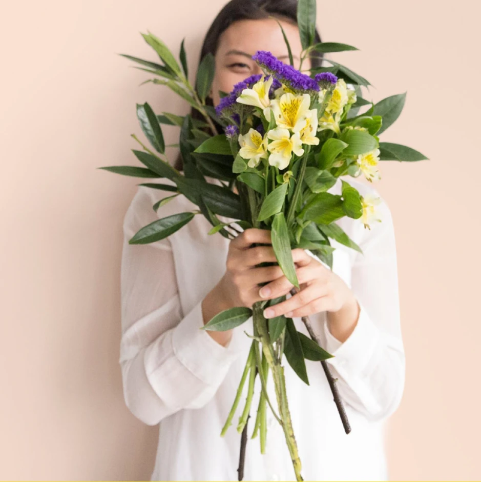 A woman holding flowers in front of her face